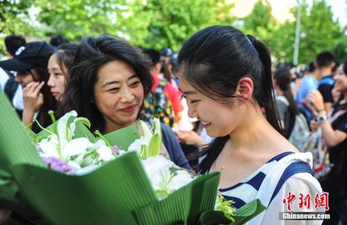 資料圖：山東濟(jì)南眾多考生手捧鮮花在家長(zhǎng)的簇?fù)硐職g快告別高考。中新社記者 張勇 攝
