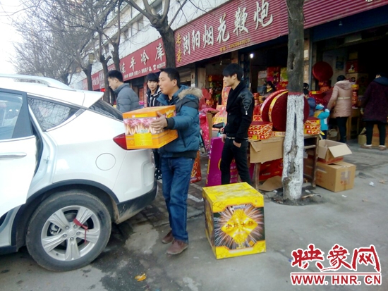 兩位年青小伙子正將買好的焰火和鞭炮往車上搬