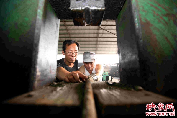 劉金玉正與工友一起用自己發(fā)明的綜合液壓機對廢舊錨桿進行軋直處理