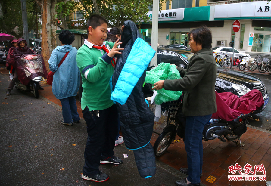學(xué)校門口，家長給孩子帶來了御寒的厚衣服。