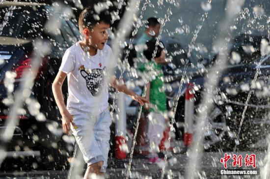 山西太原最高溫36℃,兒童在噴泉周圍戲水消暑。