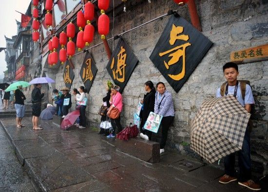 　4月29日上午11時(shí)20分，一些游客和古城當(dāng)?shù)氐木用穸阍谝粋€(gè)酒吧的屋檐下避雨。這些當(dāng)?shù)鼐用褚詾橛慰团恼罩\生，一場(chǎng)降雨讓他們的生意更加清淡。