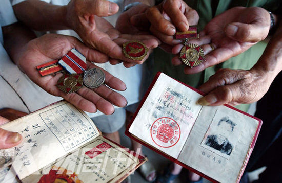 幾位志愿軍老兵展示自己的立功證、傷殘軍人證與勛章