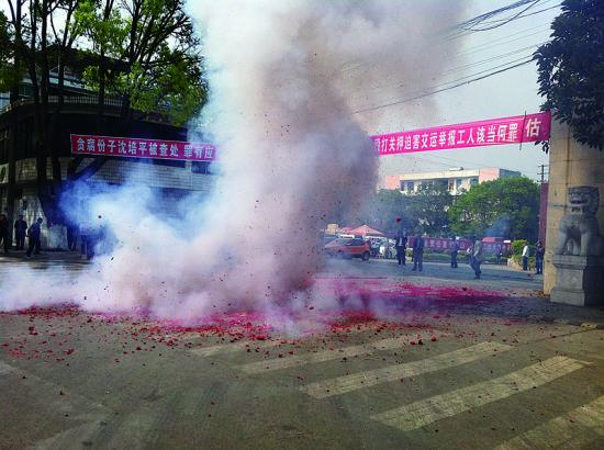 市民在普洱市主干道振興大道的金孔雀交通運(yùn)輸集團(tuán)有限公司門前燃放鞭炮，公司門前掛著“貪腐份子沈培平被查處，罪有應(yīng)得，大快人心?！钡臈l幅