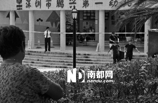 →7月19日，鵬興花園第一幼兒園門前，民警在現場進行完勘查取證后，園長和保安的尸體被運走。南都記者 徐文閣 攝