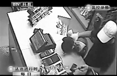 戴帽男子一手掐住加油站營業(yè)員，一手持發(fā)令槍指向另一營業(yè)員，要求“把錢給我裝起來”。