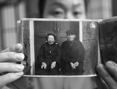 圖為孫女拿出兩位老人上世紀(jì)80年代在家門(mén)口的合影給記者看。記者楊濤 攝