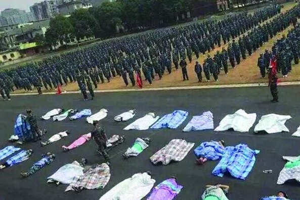 20多名女生躺在瀝青跑道上，身上嚴嚴實實地裹著棉被，接受太陽的照曬。