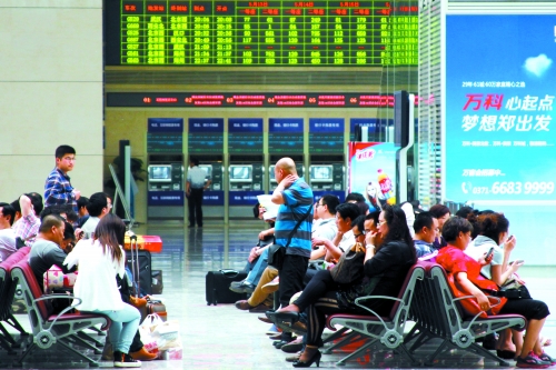 候車大廳溫度很高，一名乘客一手扇風(fēng)、一手擦汗