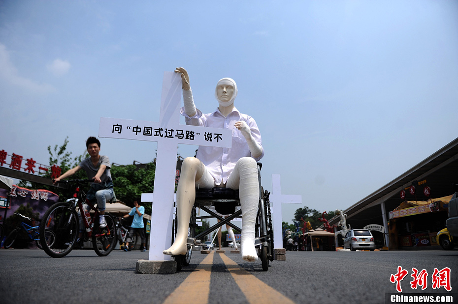 4月16日，重慶市洋人街上擺放著兩個(gè)受了傷的塑料人像“模特”，旁邊十字架上寫著向“中國式過馬路”說不