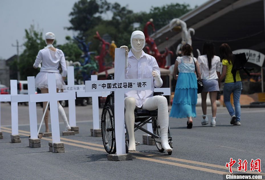 4月16日，重慶市洋人街上擺放著兩個(gè)受了傷的塑料人像“模特”，旁邊十字架上寫著向“中國式過馬路”說不