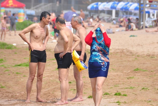 2013年7月3日，山東青島青島高溫來襲，“青島大媽”不懼滸苔，戴著“強盜面具”出現(xiàn)在海水浴場消暑降