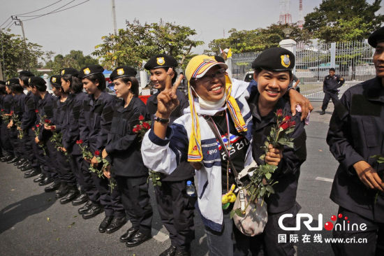 2013年12月03日,曼谷總理府與曼谷警署允許反政府示威民眾進入,雙方進入暫時“停戰(zhàn)”狀態(tài)迎接泰王生日。曼谷警察總署,女警們手持鮮花送給反政府示威民眾。圖片來源:Manish Swarup/東方IC