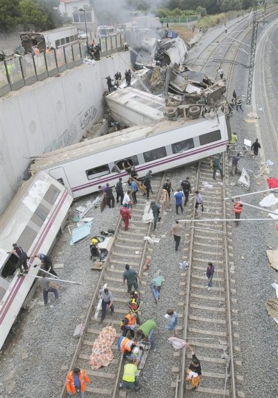24日，救援人員在西班牙列車脫軌現(xiàn)場(chǎng)。一節(jié)車廂被強(qiáng)大的慣性拋上鐵道邊的高臺(tái)。