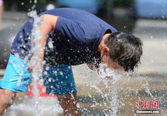 5月29日，一名小孩將頭伸向北京街頭的噴泉以降溫祛暑。