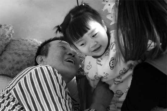 病床前李剛父女倆說著“悄悄話”，幸福的氣氛洋溢在病房中