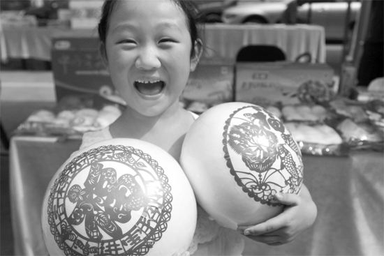 在2013河南食品安全宣傳周活動現(xiàn)場，一個小女孩抱著參展的特色大饅頭樂開了花