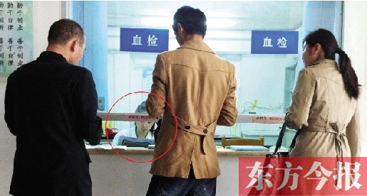 昨日，鄭州市二七區(qū)疾控中心辦證大廳，血檢窗口內(nèi)一名女工作人員，邊接受辦證者咨詢邊看報(bào)紙