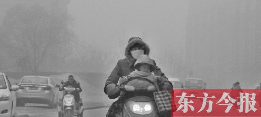 12月8日，鄭州市未來(lái)路上，一位市民帶著孩子在霧中騎行