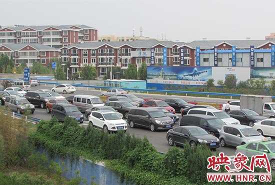 記者看到鄭州機(jī)場(chǎng)收費(fèi)站口車輛排隊(duì)，與此形成鮮明對(duì)比的是，路的對(duì)面（另一半幅）卻車輛較少，通行順暢。