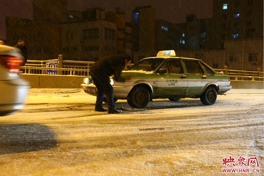 一位出租車(chē)司機(jī)在車(chē)輪前灑上雪，希望能增加輪胎的摩擦力。