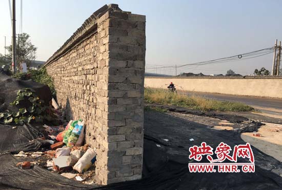 一墻之隔，一邊是道路，一邊是垃圾和荒草，市民質(zhì)疑其為遮羞墻。
