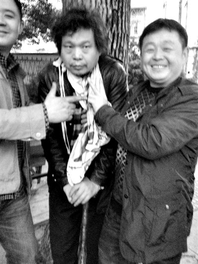 兩名接訪人員與患有癌癥的訪民段新德合影時(shí)，面帶笑容擺出勝利的手勢(shì)。