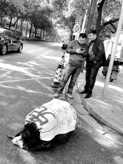 兩名接訪人員與患有癌癥的訪民段新德合影時(shí)，在拍照時(shí)查看手機(jī)。