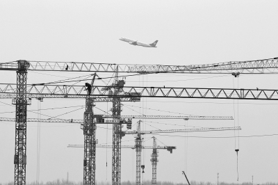 空中是起飛的飛機(jī)，下面是T2航站樓工地上林立的塔吊
