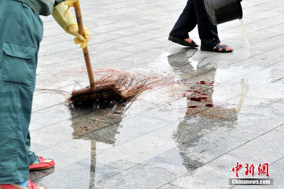 圖為環(huán)衛(wèi)工人在清理案發(fā)地點(diǎn)的血跡。