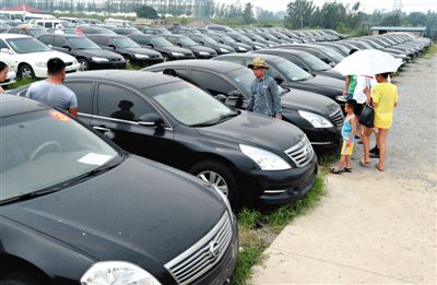 昨日，市民在山東棗莊一家拍賣公司場地上查看待拍賣公車。當(dāng)日，棗莊市103輛公車公開拍賣。新華社記者