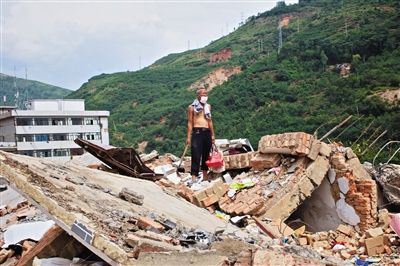 8月9日,龍頭山鎮(zhèn),一位老者在自家房屋廢墟上尋找家當(dāng)。
