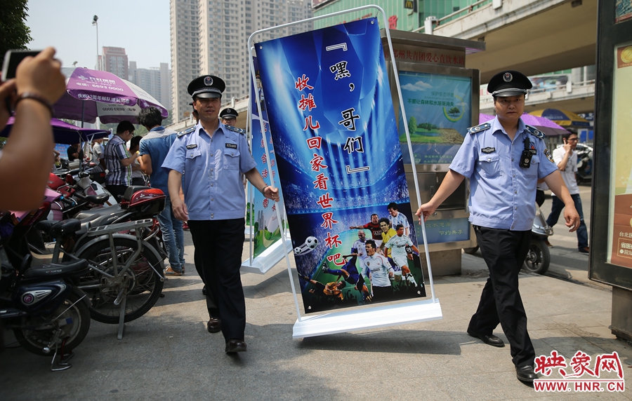 7月2日上午，鄭州市紫荊山地鐵站出入口，執(zhí)法人員抬著寫有勸導(dǎo)語的宣傳板，前往占道經(jīng)營攤位“圍觀執(zhí)法”