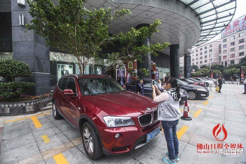一輛停在停車位上的寶馬轎車，被墜落的樹枝砸中，樹枝徑直插入車內(nèi)，現(xiàn)場(chǎng)引發(fā)不少市民圍觀拍照。
