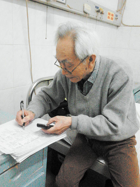 杜修源老人埋頭寫著特殊的“日記”。 李卓 攝